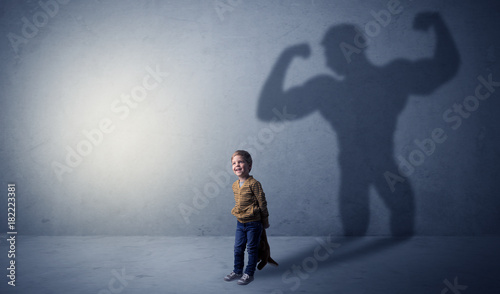 Muscleman shadow behind waggish little boy
