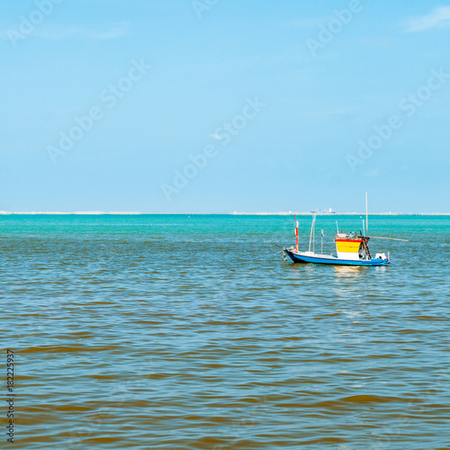 Small Blue Yellow wooden fishing boat in the sea