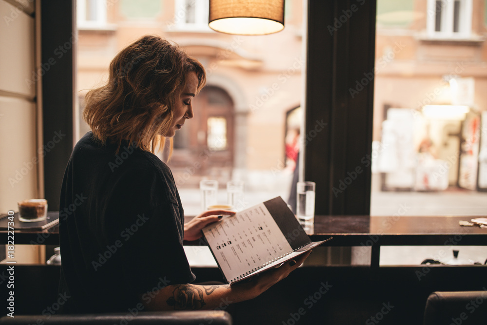 Pretty girl drinking coffee and reading a menu in a bar Pretty girl drinking coffee and reading a menu in a bar