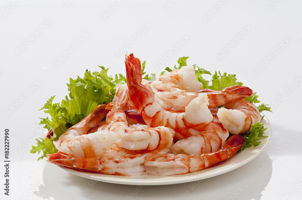 Steamed Jumbo headless shrimps with deli leaves and Lemon on white plate on white background 
