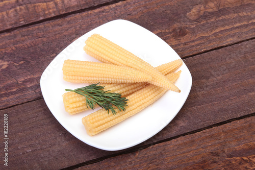 Mini Corn cob preserved on plate on wooden board. photo