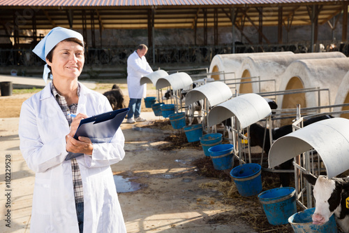 Woman veterinarian with clipboard at cowshed