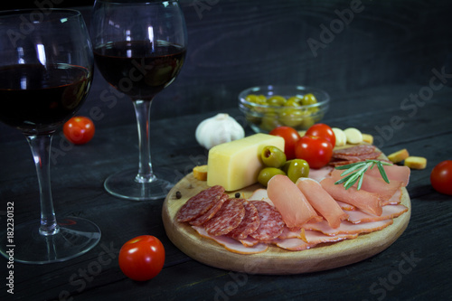 Appetizer on a wooden board with wine and olives for two. Romantic dinner