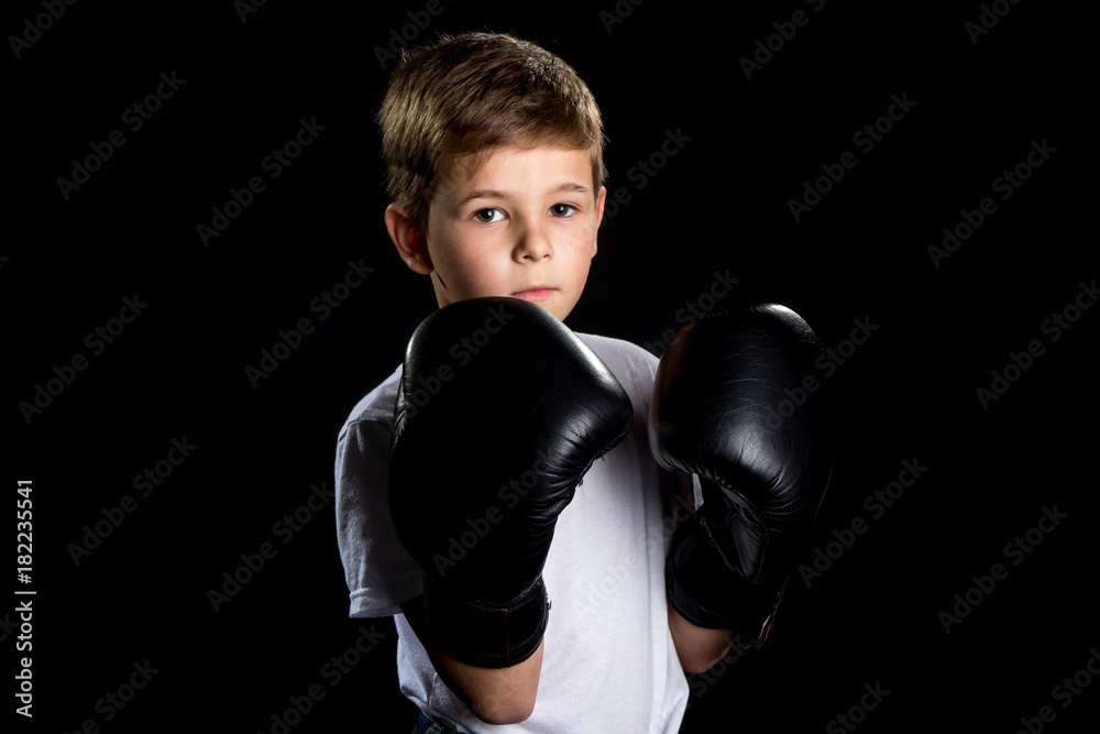 Little boxer portrait in black boxing gloves in defensive position Little boxer portrait in black boxing gloves in defensive position