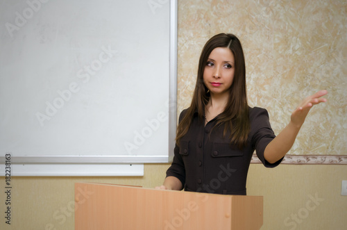 Lecture. Lesson. Exam pass. Young woman teacher answers on questions and addresses the students in the classroom. Education concept.
