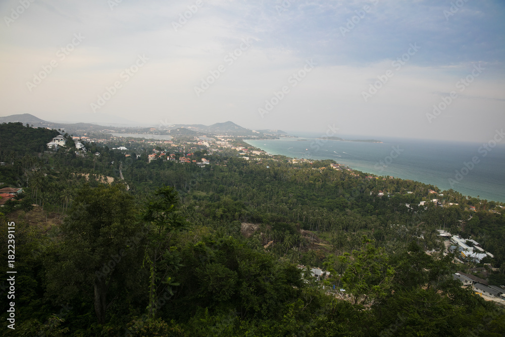 Samui Island. A beautiful view of the green mountains. View of the jungle and palm trees and the coast from high mountain. Clear sky.