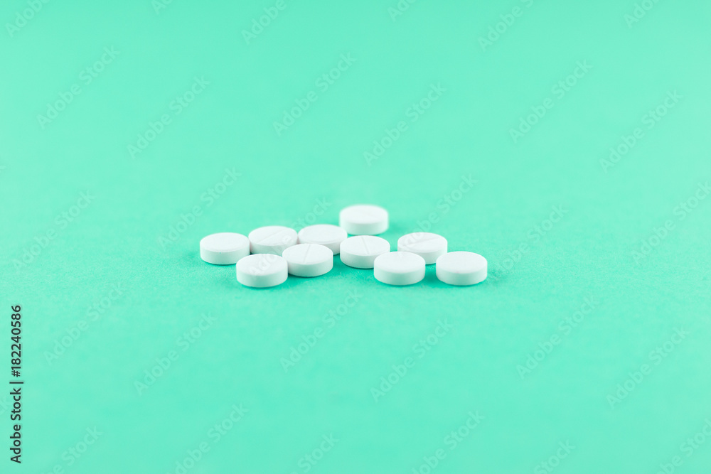 White pills with copy space on aquamarine background. Focus on foreground, soft bokeh White pills with copy space on aquamarine background. Focus on foreground, soft bokeh