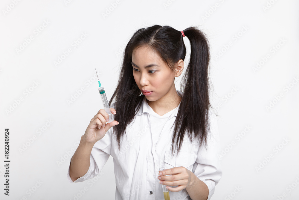 custom made wallpaper toronto digitalSerious concentrated young Chinese female chemist with two ponytails holding test tube with liquid solution in one hand and looking at syringe in other while carrying out laboratory experiment