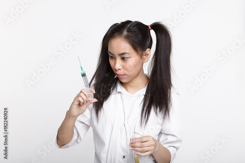 Wallpaper Mural Serious concentrated young Chinese female chemist with two ponytails holding test tube with liquid solution in one hand and looking at syringe in other while carrying out laboratory experiment Torontodigital.ca