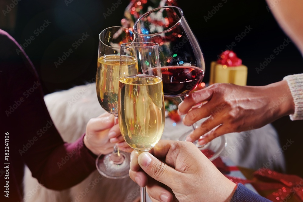 Christmas or New Year Celebration people hands with crystal glasses full of champagne near the Christmas tree and space for your text.