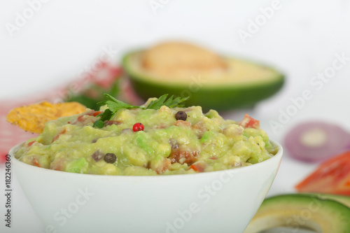 Guacamole with avocado, lime, tomato, and cilantro with tortilla chips.