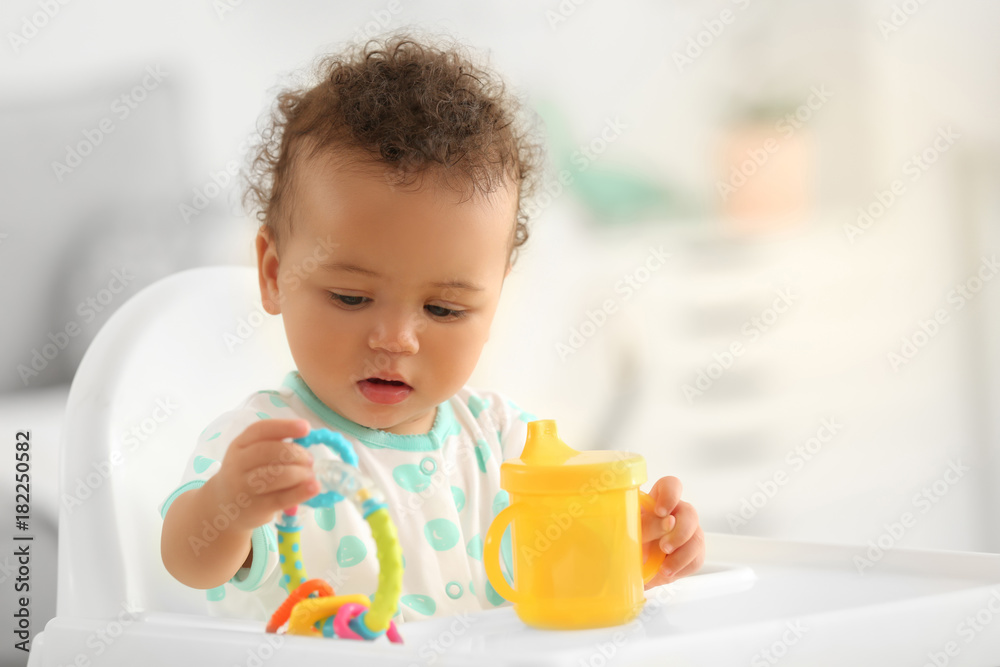 Cute baby with bottle of water sitting on chair indoors Cute baby with bottle of water sitting on chair indoors