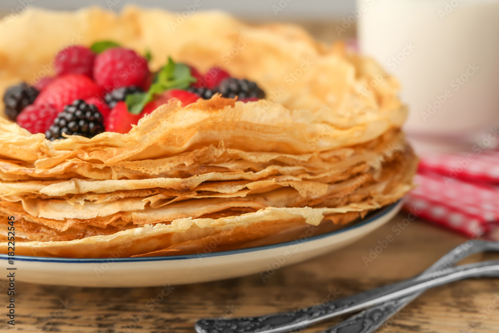 Plate of delicious thin pancakes with berries on wooden table, closeup Plate of delicious thin pancakes with berries on wooden table, closeup