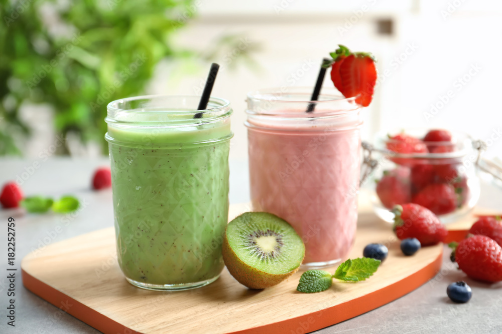 Glass jars with different milkshakes on wooden board Glass jars with different milkshakes on wooden board