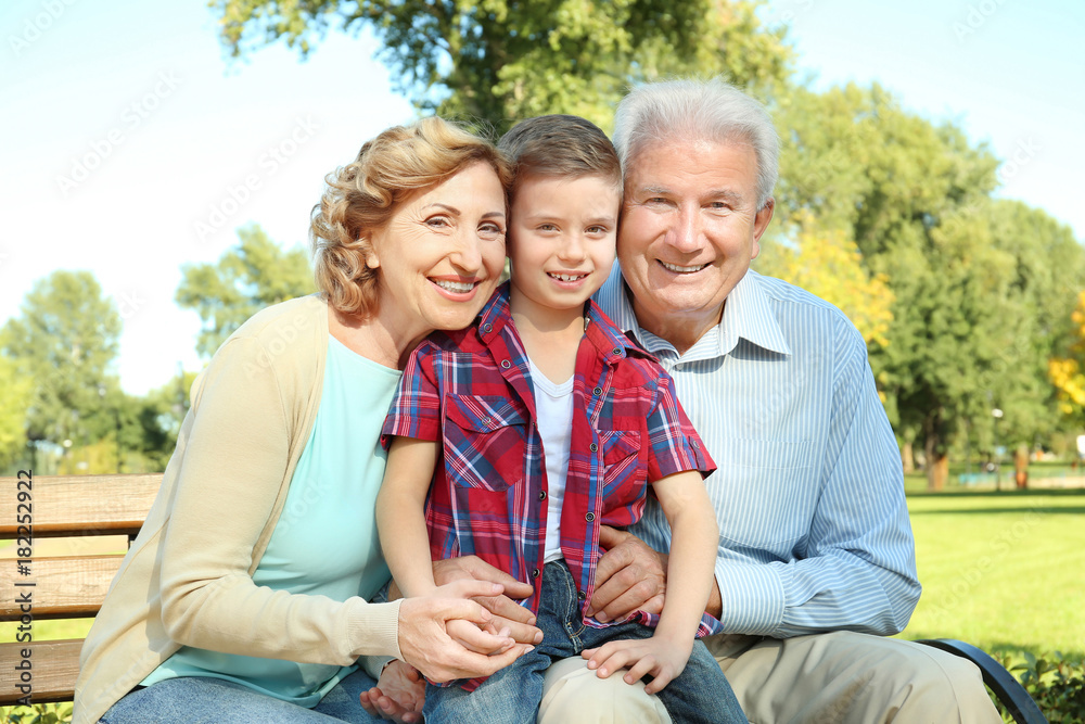 Elderly couple with grandson sitting on bench in park Elderly couple with grandson sitting on bench in park
