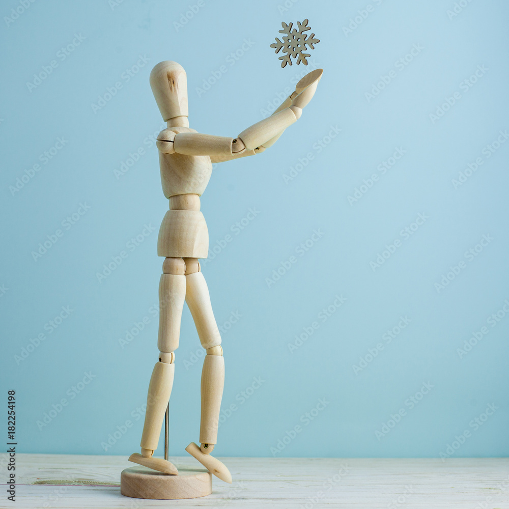 Minimal winter concept. Wooden manikin is trying to catch snowflake Minimal winter concept. Wooden manikin is trying to catch snowflake