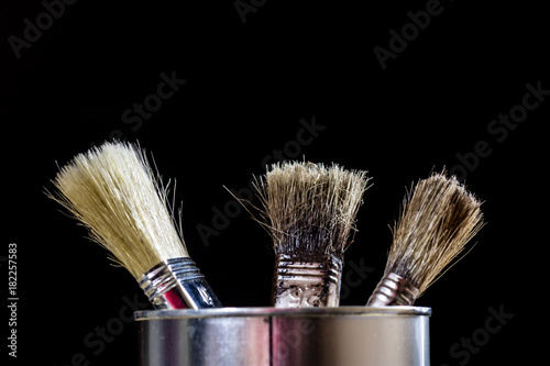 Old paintbrushes for paint, Cans of paint on wooden table. Painting workshop.