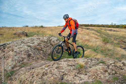 Cyclist in Red Riding the Bike on Autumn Rocky Trail. Extreme Sport and Enduro Biking Concept. © Maksym Protsenko