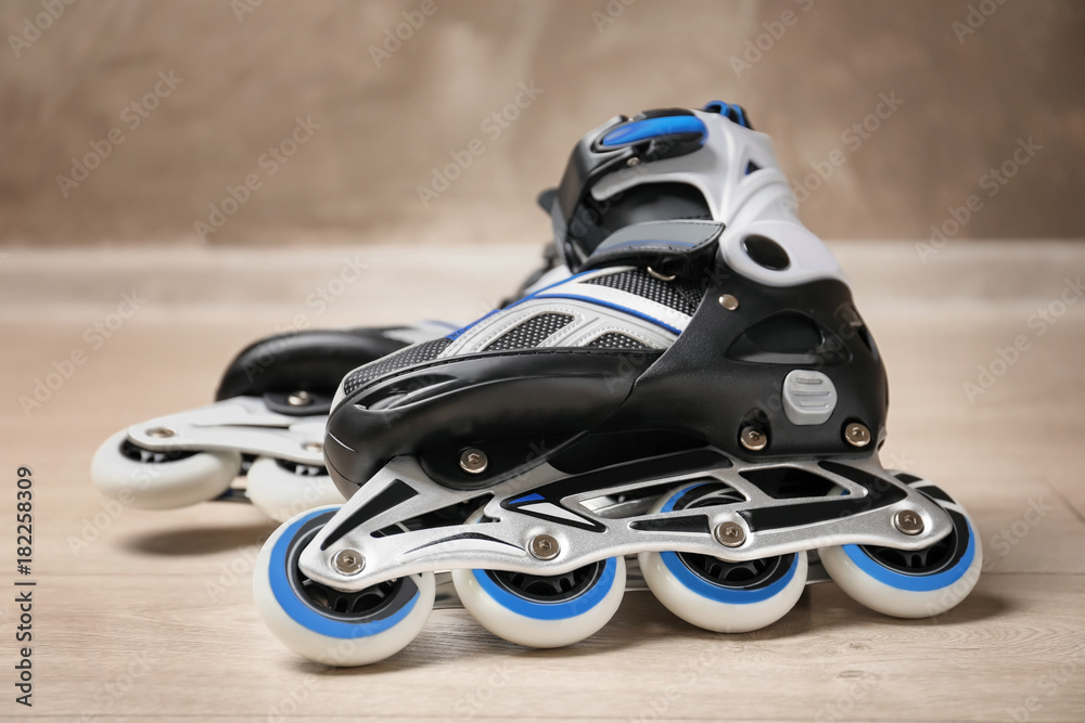 Pair of roller skates on floor against light wall