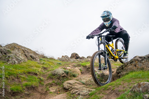 Professional Cyclist Riding Mountain Bike Down the Rocky Hill. Extreme Sport and Enduro Biking Concept.