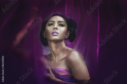 Young Asian Woman Tanned Skin And Black Shine Hair in glamorous purple dress, fancy face make up. © orapin