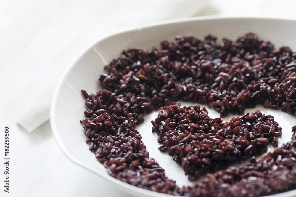 Thai jasmine black rice in heart shape on white ceramic plate Thai jasmine black rice in heart shape on white ceramic plate