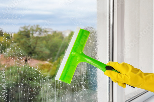 Obraz na plátne Cleaner washing window with squeegee