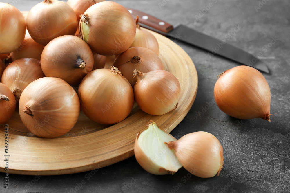 Plate with fresh raw yellow onion on grey background Plate with fresh raw yellow onion on grey background