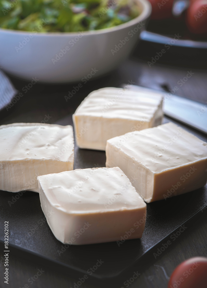 Feta cheese with greek salad and tomatoes on the brown wood table 