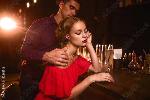Woman in dress and man behind bar counter  flirt