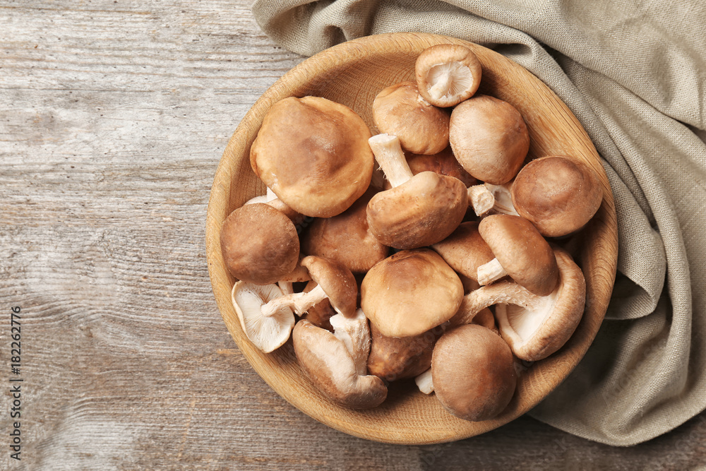 Bowl with raw shiitake mushrooms on wooden table Bowl with raw shiitake mushrooms on wooden table