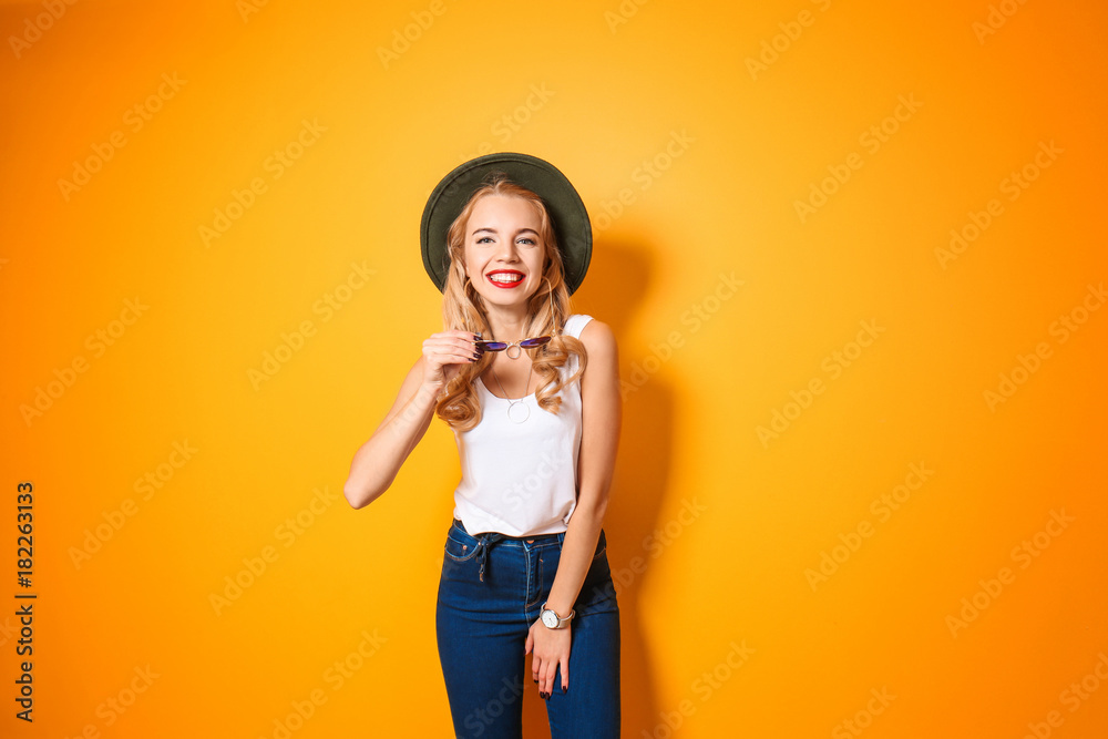 Attractive hipster girl with hat and sunglasses on color background Attractive hipster girl with hat and sunglasses on color background