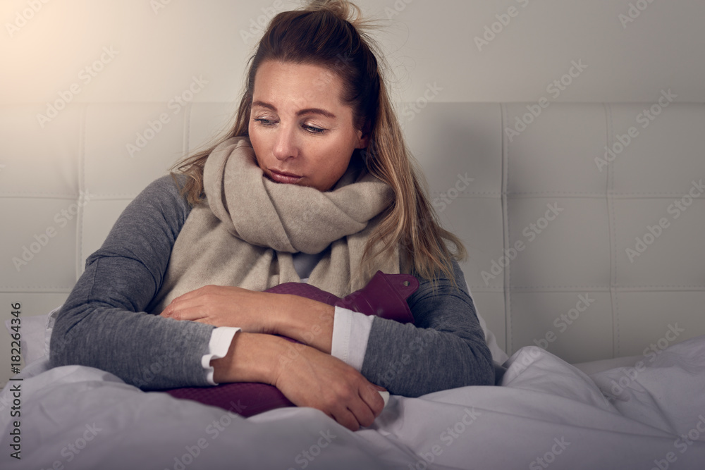 Frau mit Wärmflasche liegt im Bett Stock Photo | Adobe Stock