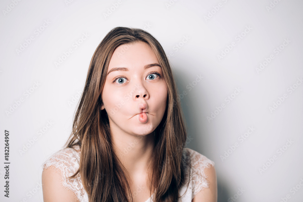 Close up indoor fashion lifestyle portrait of pretty young brunette girl,  long hairs, cute face, making crazy funny grimace. funny woman on white  background, emotions Stock Photo | Adobe Stock