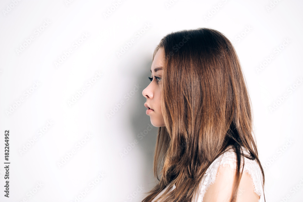Portrait of girl in profile. Beautiful woman has a clean well-groomed skin and long straight hair. Close-up portrait against a light gray background. Portrait of girl in profile. Beautiful woman has a clean well-groomed skin and long straight hair. Close-up portrait against a light gray background.