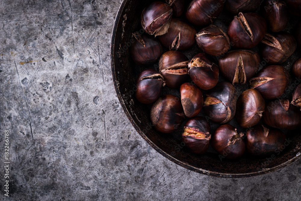 Fototapeta premium Roasted chestnuts on an old board. healthy food concept
