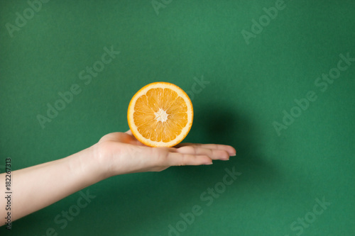 Tasty orange in a hand. holding a orange isolated on a colored background