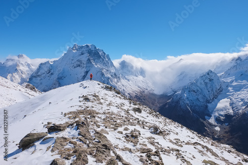 Landscape in the high Caucasus mountains with a female tourist on top peak