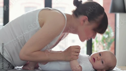 Mother gently kissing baby on the changing table at home
