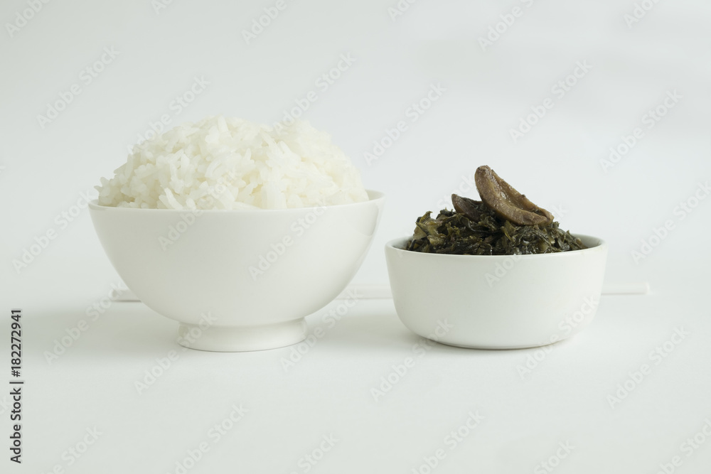 STEAMED RICE AND PRESERVED LETTUCE
Chinese style preserved lettuce are served with steamed rice in a white bowl on white background. STEAMED RICE AND PRESERVED LETTUCE
Chinese style preserved lettuce are served with steamed rice in a white bowl on white background.