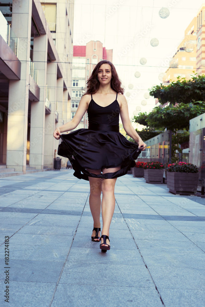 Happy young woman walks through a deserted city square