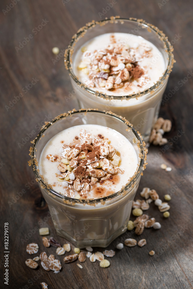 creamy cocktail with muesli on dark background, top view
