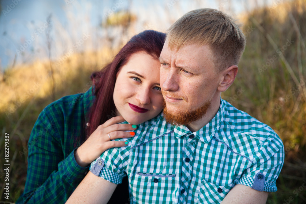 Young loving married couple on the river bank, man and beautiful girl on nature in summer