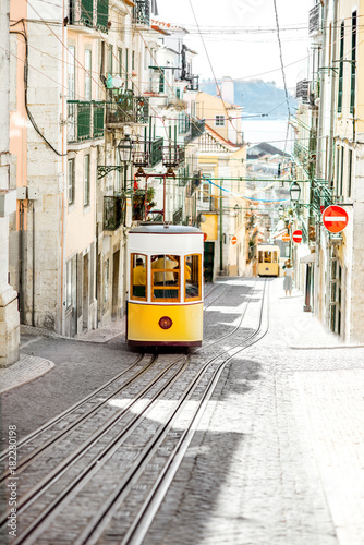 Street view with famous yellow funicular tram in Lisbon during the sunny day in Portugal photo