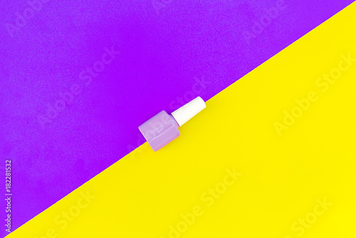 Bright decorative cosmetics. Llilac nail polish on blue and yellow background top view
