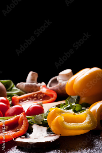 Healthy organic lifestyle concept image with different vegetables on the table. Radish, greengrocery, cutted yellow and red pepper and mushrooms. Copy space available for your text