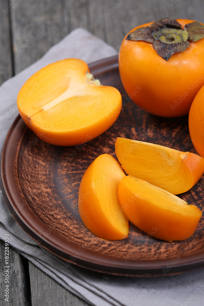Japanese persimmons in ceramic plate. Closeup Japanese persimmons in ceramic plate. Closeup