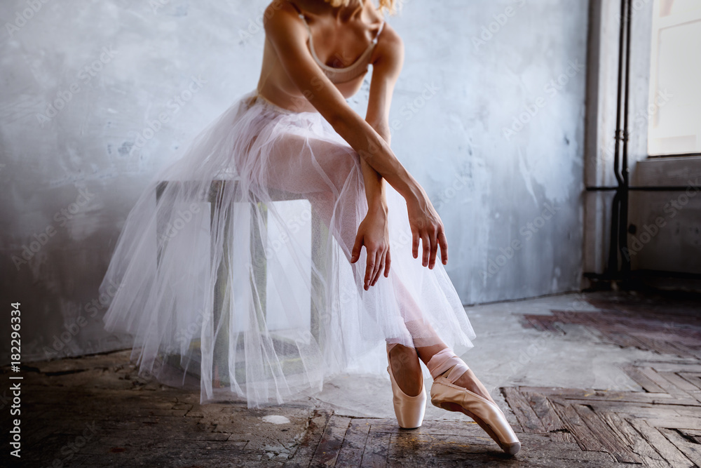 Obraz premium Młoda i szczupła tancerka baletowa pozuje w stylowym studio z dużymi oknami