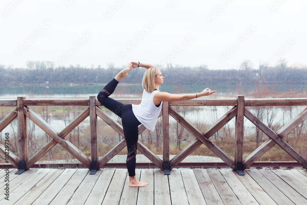 Portrait of young woman practicing yoga pose outdoors on nature. Beautiful girl practice Natarajasana pose. Calmness and relax, female happiness concept