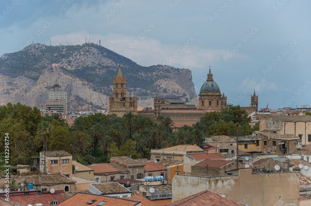 Sicilian town of Palermo skyline over roofs of historic buildings with the mountains in the background. Italy